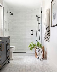 a white bathroom with black and gold accessories on the vanity, shower, and toilet