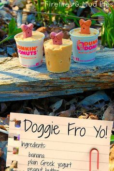 three frozen yogurt cups sitting on top of a wooden table next to a sign that says doggie fro yo