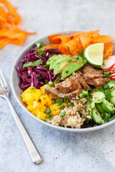 a white bowl filled with meat, veggies and rice next to a fork