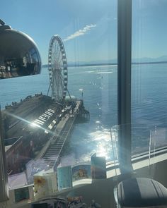 a ferris wheel sitting on top of a pier next to the ocean in front of a window