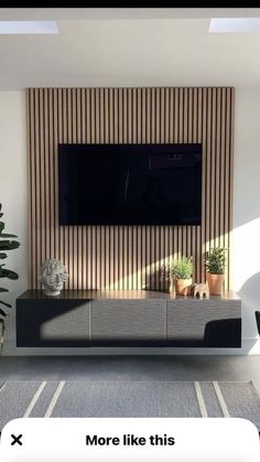 a flat screen tv mounted to the side of a wall in front of a potted plant