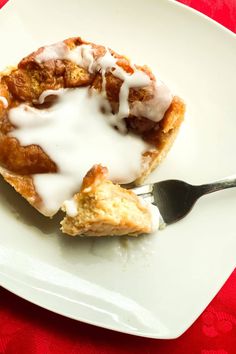 a white plate topped with a pastry covered in icing and sitting next to a fork