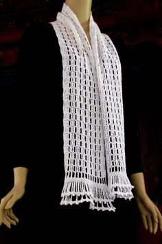 a mannequin wearing a white crochet scarf on top of a table