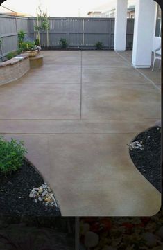 a concrete patio with raised planters and landscaping