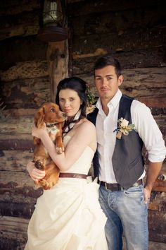 a man and woman in wedding attire holding a puppy dog posing for a photo together