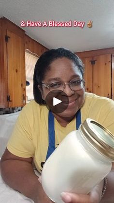 a woman is holding a jar with milk in it and smiling at the camera while sitting on a bed