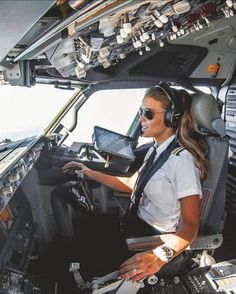 a female pilot sitting in the cockpit of an airplane with headphones on her ears