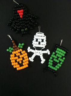 three beaded halloween ornaments on a black surface, one has a pumpkin and the other has a skeleton