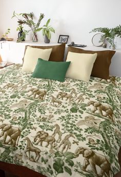 a bed with green and brown pillows on top of it next to potted plants