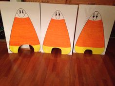 three paper bags with faces on them sitting on a wooden floor in front of a cabinet