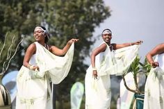 three women dressed in white are dancing