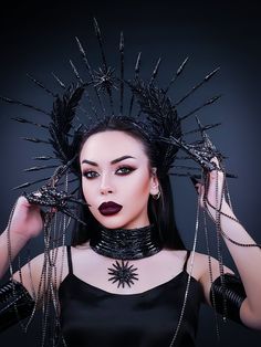 Gorgeous black gothic crown with spikes made of zip ties coated with liquid plastic. The crown is decorated with natural feathers coated with liquid plastic, the center of the crown is decorated with a sun icon, as well as rhinestones and glass rhinestones on a metal ribbon. Ideal for special occasions and fine costumes, as well as holidays, festivals and celebrations. The crown will be an excellent prop for artistic photography.  The size of this headgear is universal for an adult. It sits soft Sunburst Crown, Crown Dark, Gothic Crown, Festival Headpiece, Feather Coat, Goddess Crown, Avant Garde Hair, Goddess Of Victory, Halo Crown