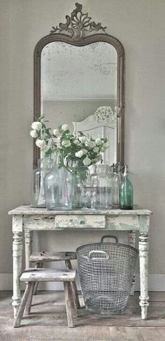 a white table topped with lots of vases and flowers next to a large mirror