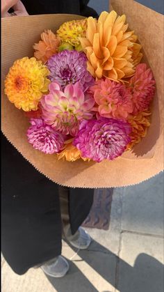 a person holding a paper bag with flowers in it