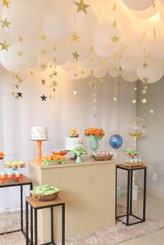 the dessert table is set up with balloons and stars hanging from the ceiling above it