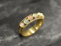 a gold ring with opals on it sitting on top of a stone slabd surface