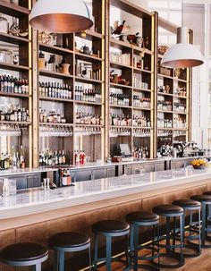 the bar is lined with bottles and stools