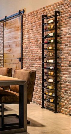 a dining room table and chairs with wine bottles on the wall behind it in front of a brick wall