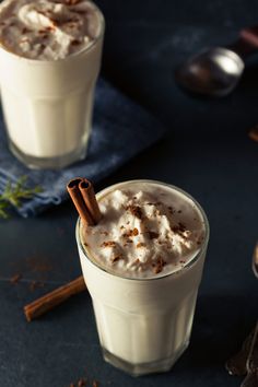 two glasses filled with whipped cream and cinnamon sticks