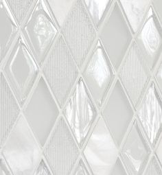 a close up view of a glass mosaic tile wall with white and clear squares on it