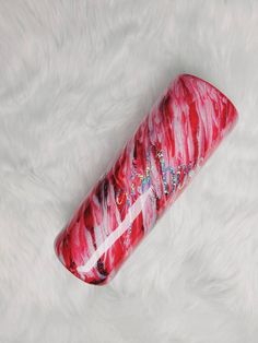 a red and white tube sitting on top of a white fur covered floor next to a bottle