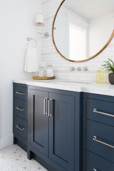 a bathroom with blue cabinets and a round mirror