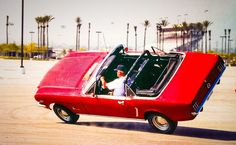 a man in a red car driving down the street