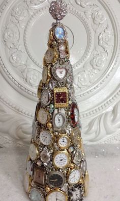 a small christmas tree made out of watches and watch parts on a white marble surface