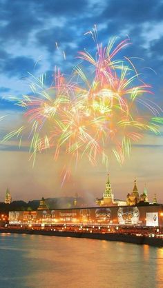 fireworks in the sky over a river with buildings on both sides and water below it