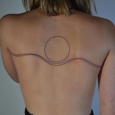 a woman's back with a tattoo on her left shoulder and an object in the middle