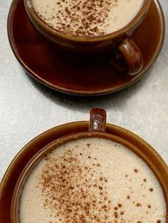 two brown cups filled with liquid on top of a table