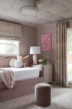 a bedroom with pink walls and carpeted flooring is decorated in shades of gray