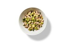 a white bowl filled with chopped vegetables on top of a white countertop next to a spoon