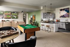 a pool table in the middle of a living room with bar stools around it