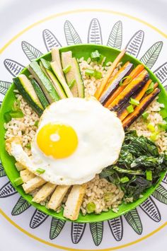 a green plate topped with rice, vegetables and an egg