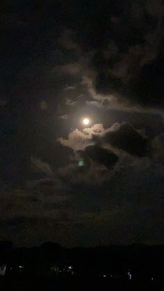 the full moon is shining brightly in the night sky with clouds and trees around it