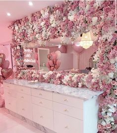 a room decorated in pink and white with lots of flowers on the walls, mirrors and dressers