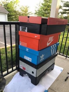 a stack of nike boxes sitting on top of a white piece of paper in front of a fence