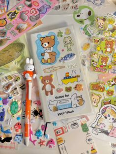 various stickers, pens and markers on a table with some paper goods in the background