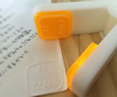 an orange rubber stamp sitting on top of a piece of paper next to a white eraser