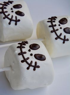 three marshmallows decorated with chocolate and white frosting