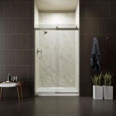 a bathroom with a walk in shower sitting next to a table and chair on the floor