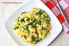 a white plate topped with scrambled eggs and spinach