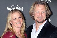 a man and woman standing next to each other in front of a hard rock sign