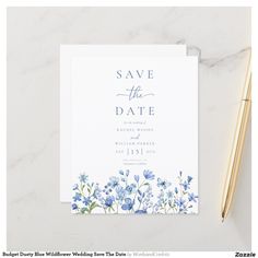 save the date card with blue flowers on it next to a pen and paper clip