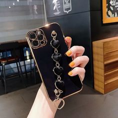 a woman holding up her phone case with charms attached to the front and back sides