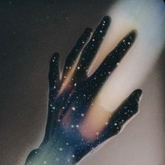 a person's hand reaching out to the sky with stars on it and light coming from behind