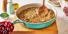 a blue pot filled with mushrooms and broth on top of a wooden cutting board