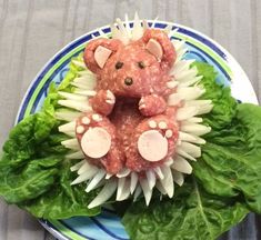 a plate topped with meat and vegetables on top of lettuce, tomatoes and tomato slices