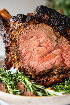 a piece of meat sitting on top of a white plate covered in green herbs and garnish